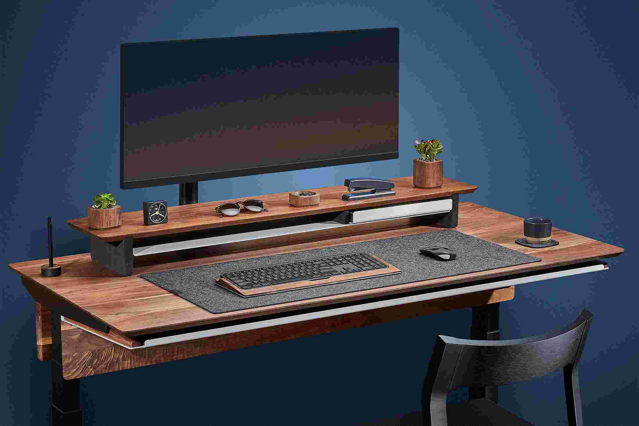 Side view of the hardwood walnut standing desk with monitor arm and premium felt desk pad.