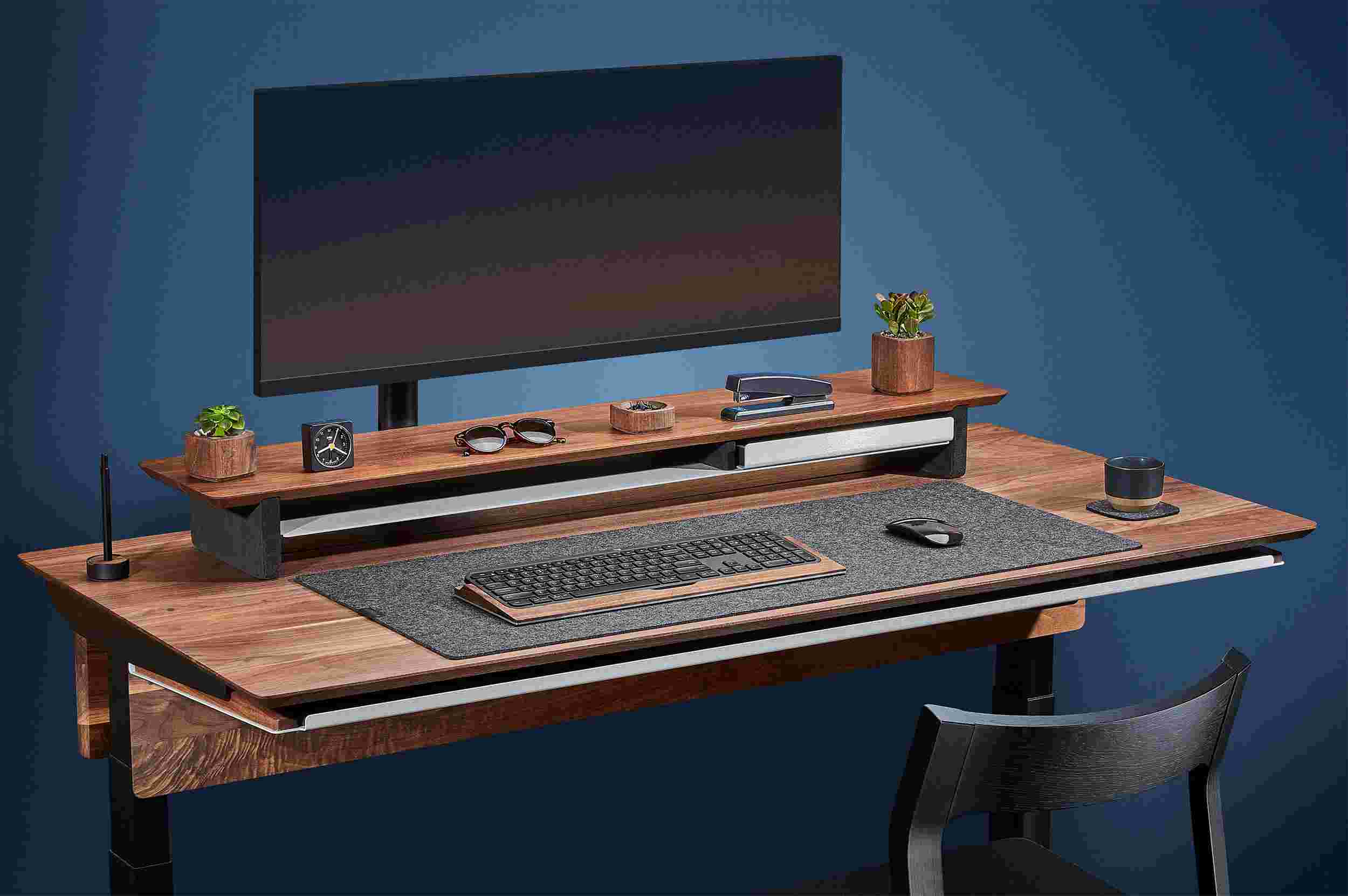 Side view of the hardwood walnut standing desk with monitor arm and premium felt desk pad.
