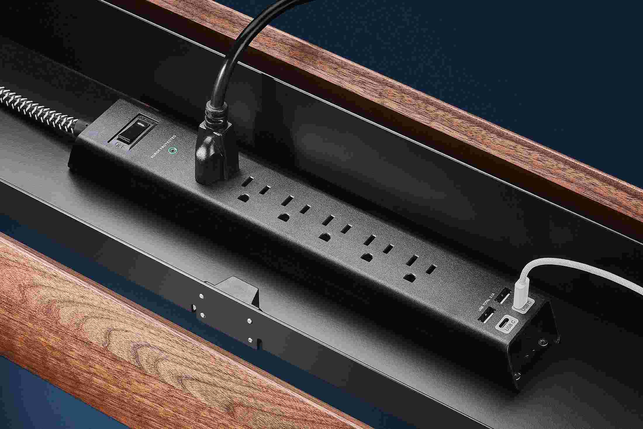 Internal view of the integrated 6-outlet surge protector inside the walnut power panel.