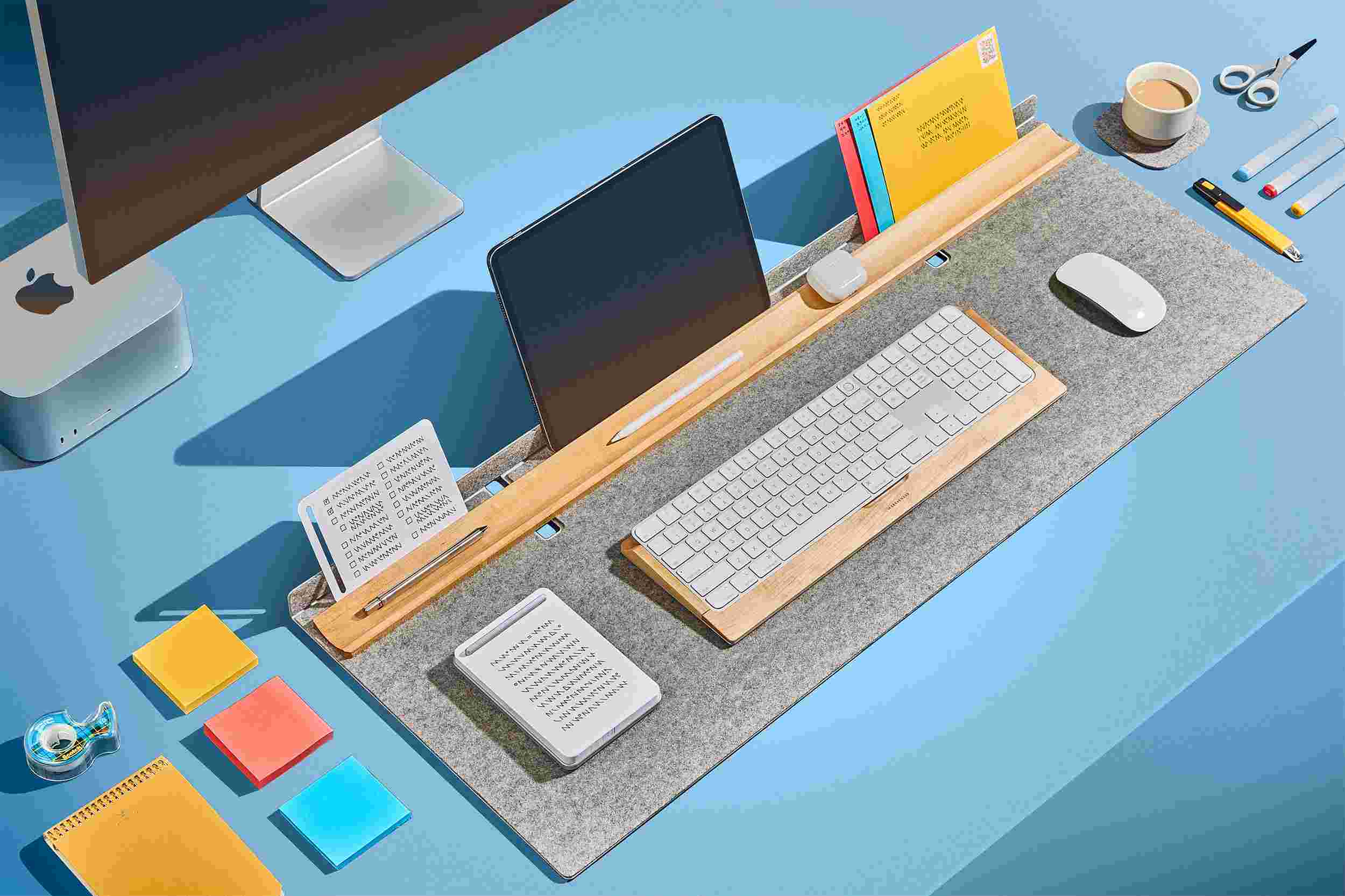 Light wool felt desk pad with built in maple tray on blue background with built in stand for iPad.