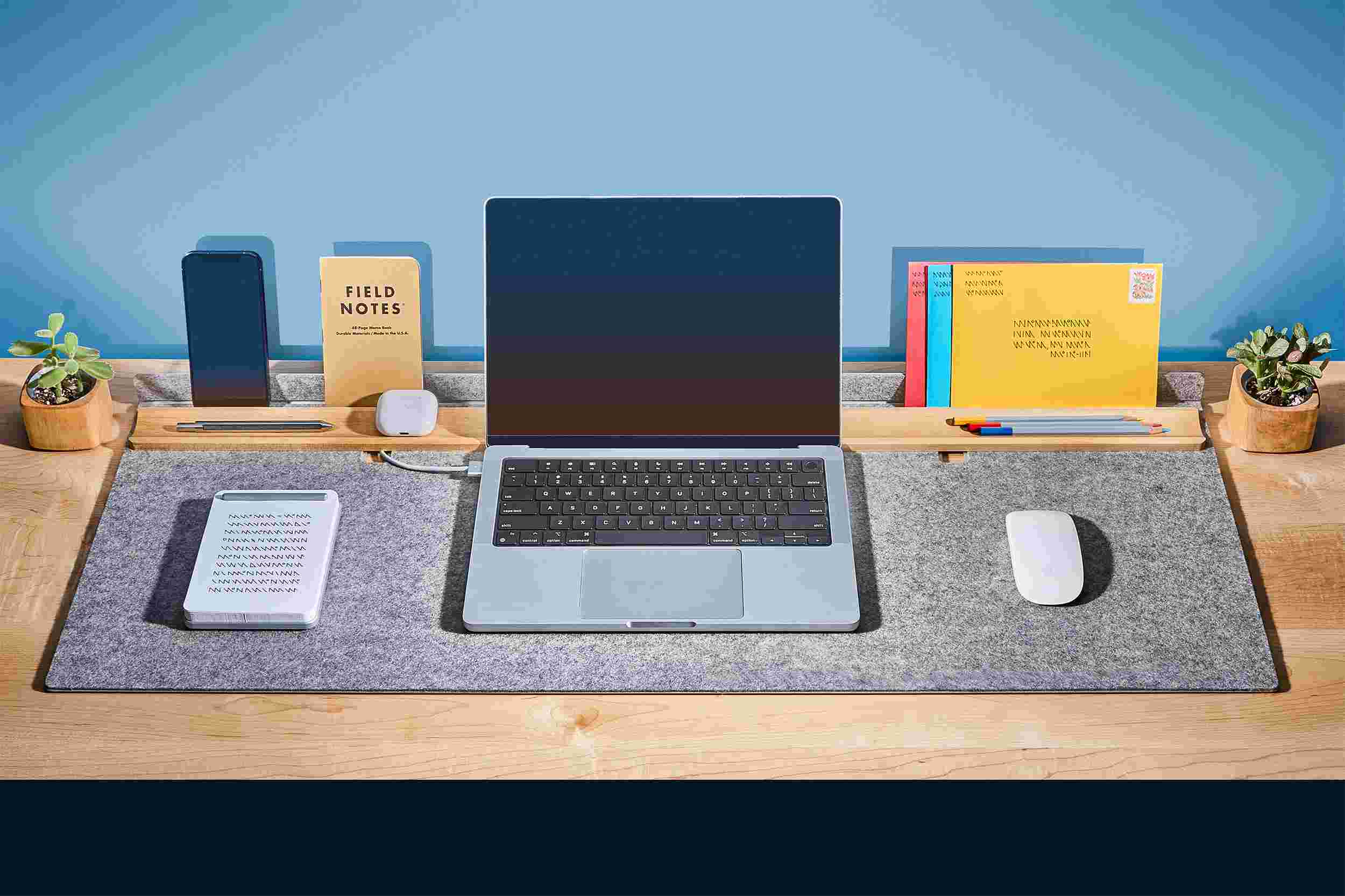 MacBook Pro on the light grey studio pad with cord management for charger.