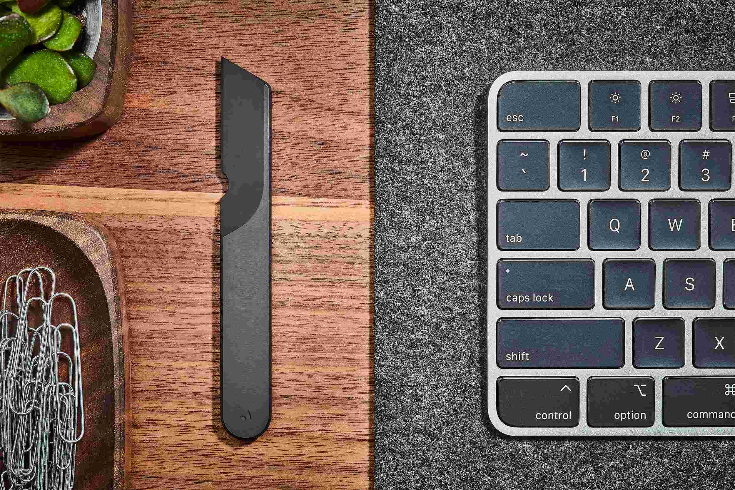 Overhead view of black desk knife on walnut desk.