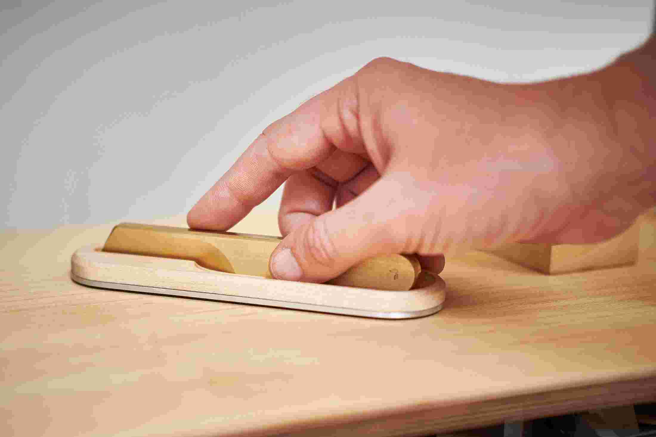 Solid brass knife being placed into maple wood knife holder.
