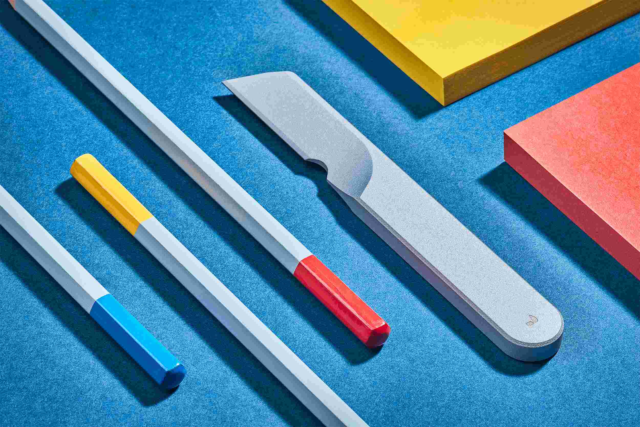 Sculptural silver task knife on blue background.