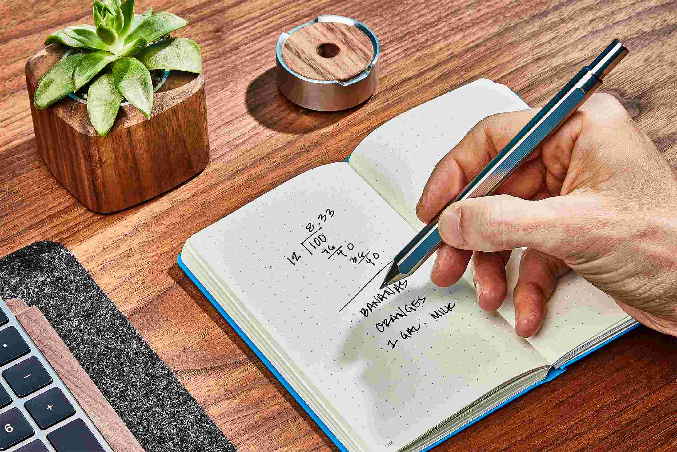 The Grovemade Titanium Pen in use, writing in a notebook.