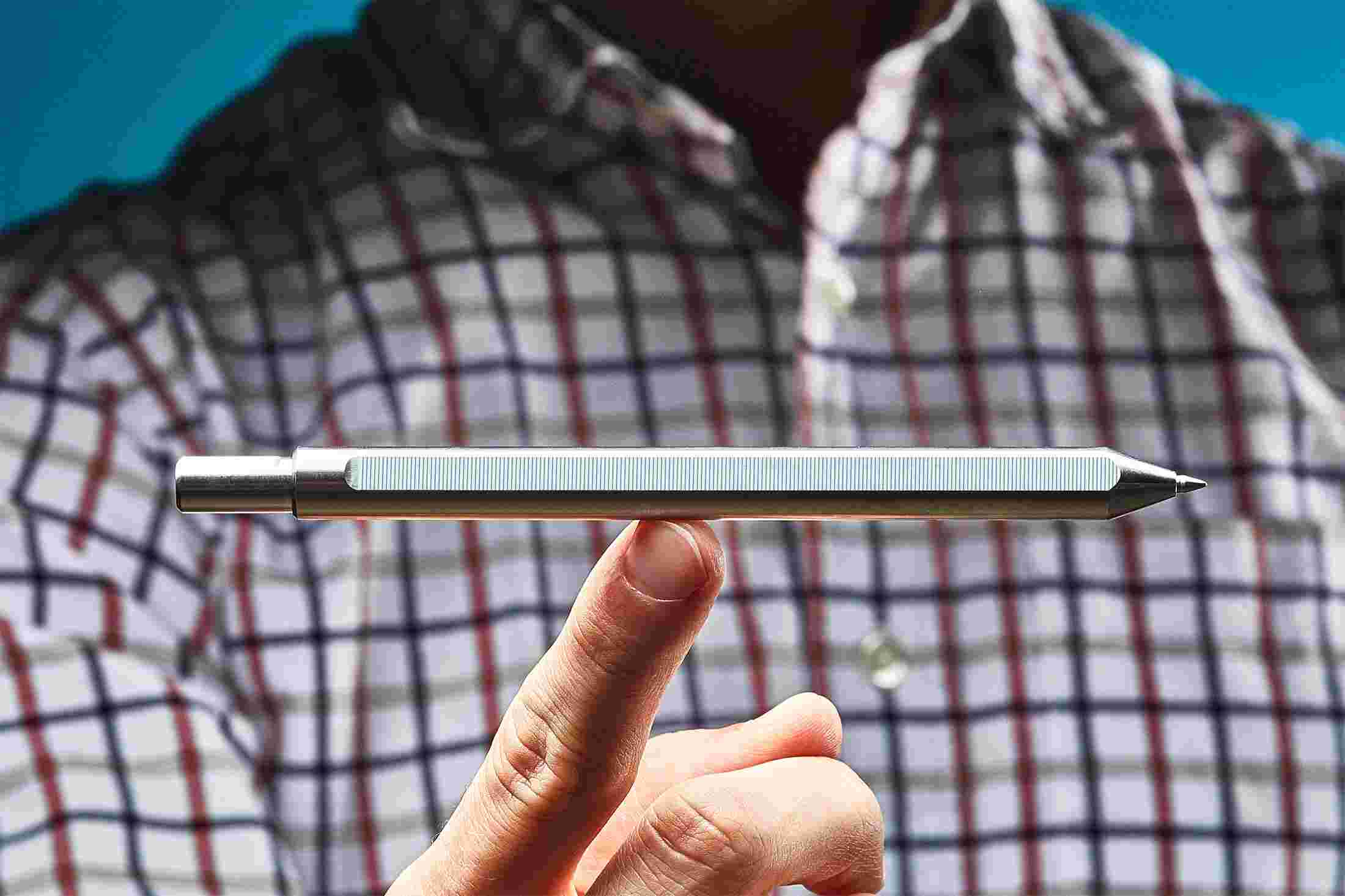 The titanium pen perched on a single finger, showing the extreme balance of the minimalist design.