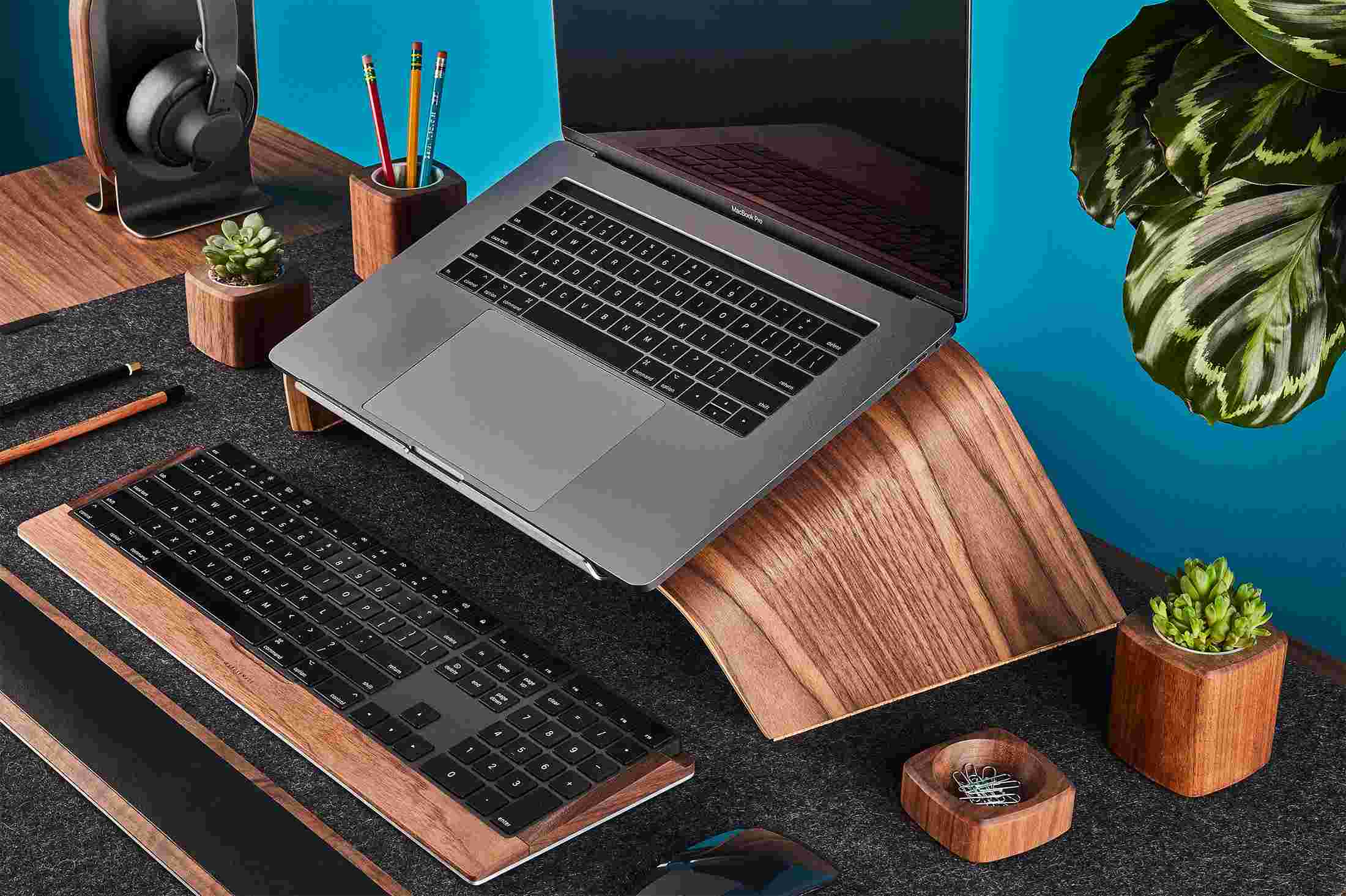 Walnut Wood Grovemade Desk Collection with walnut laptop stand, pen cups, desk lamps, planter, leather mouse pad, leather wrist pad, and keyboard tray.
