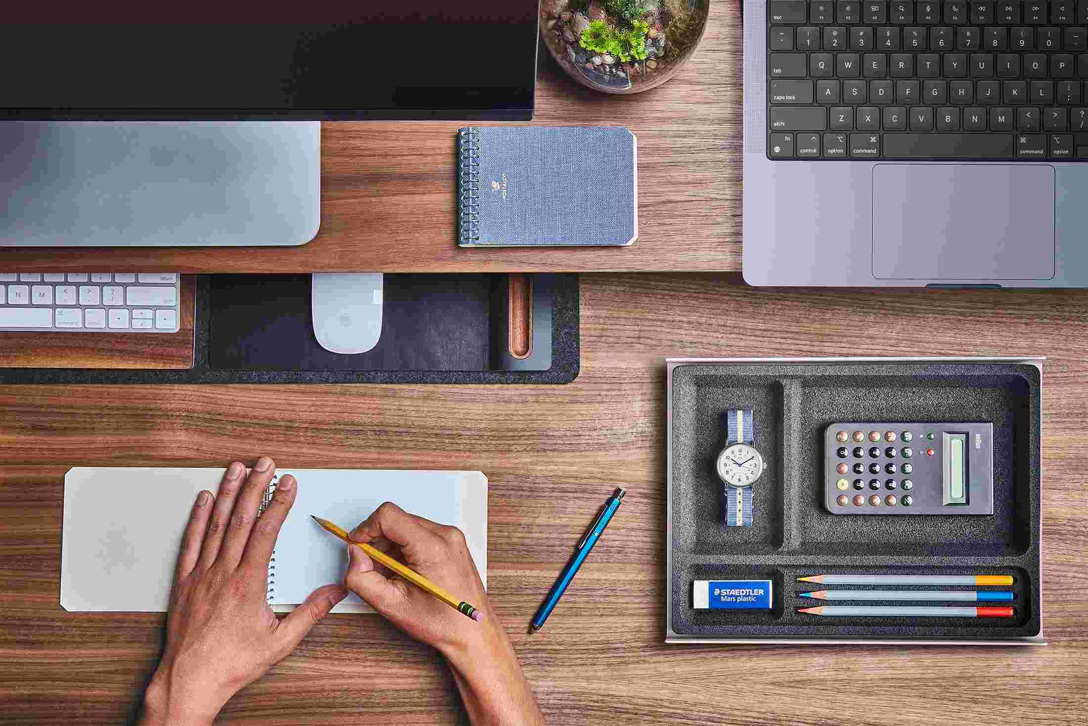 Overhead of the small desk pad with keyboard and mouse slid under the desk shelf to free up desk space.