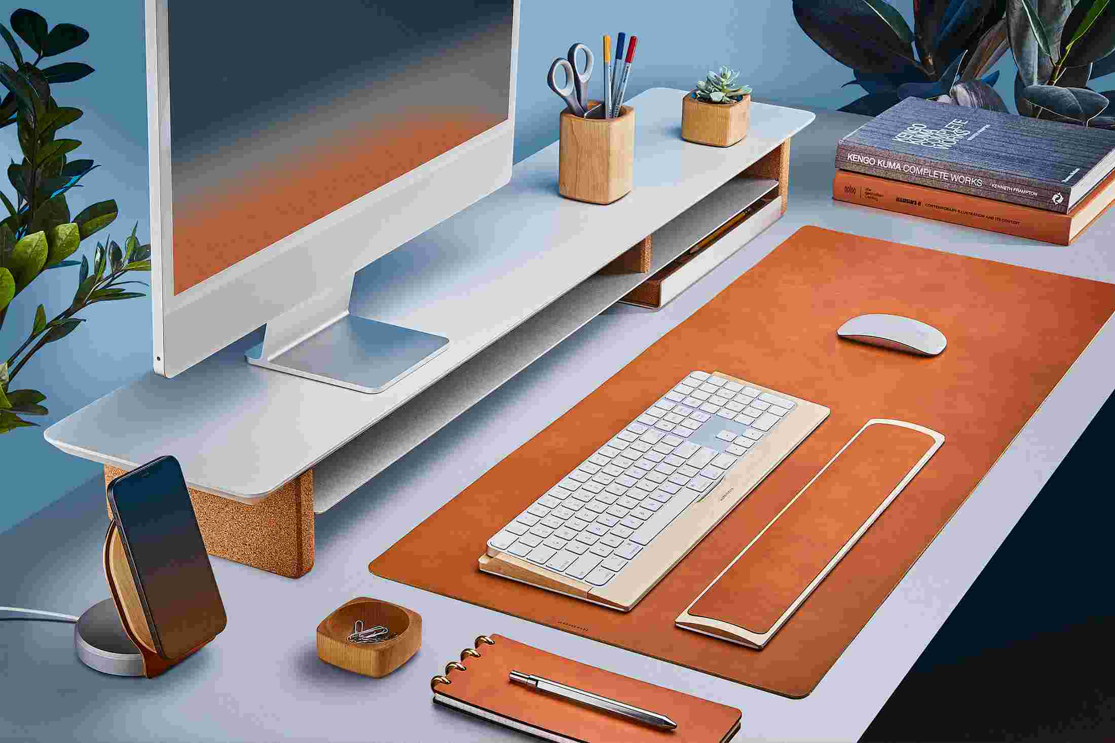The Medium Plus Wool Felt Desk Pad runs the entire width of a standard desk, pictured here with walnut wood double-wide monitor stand.
