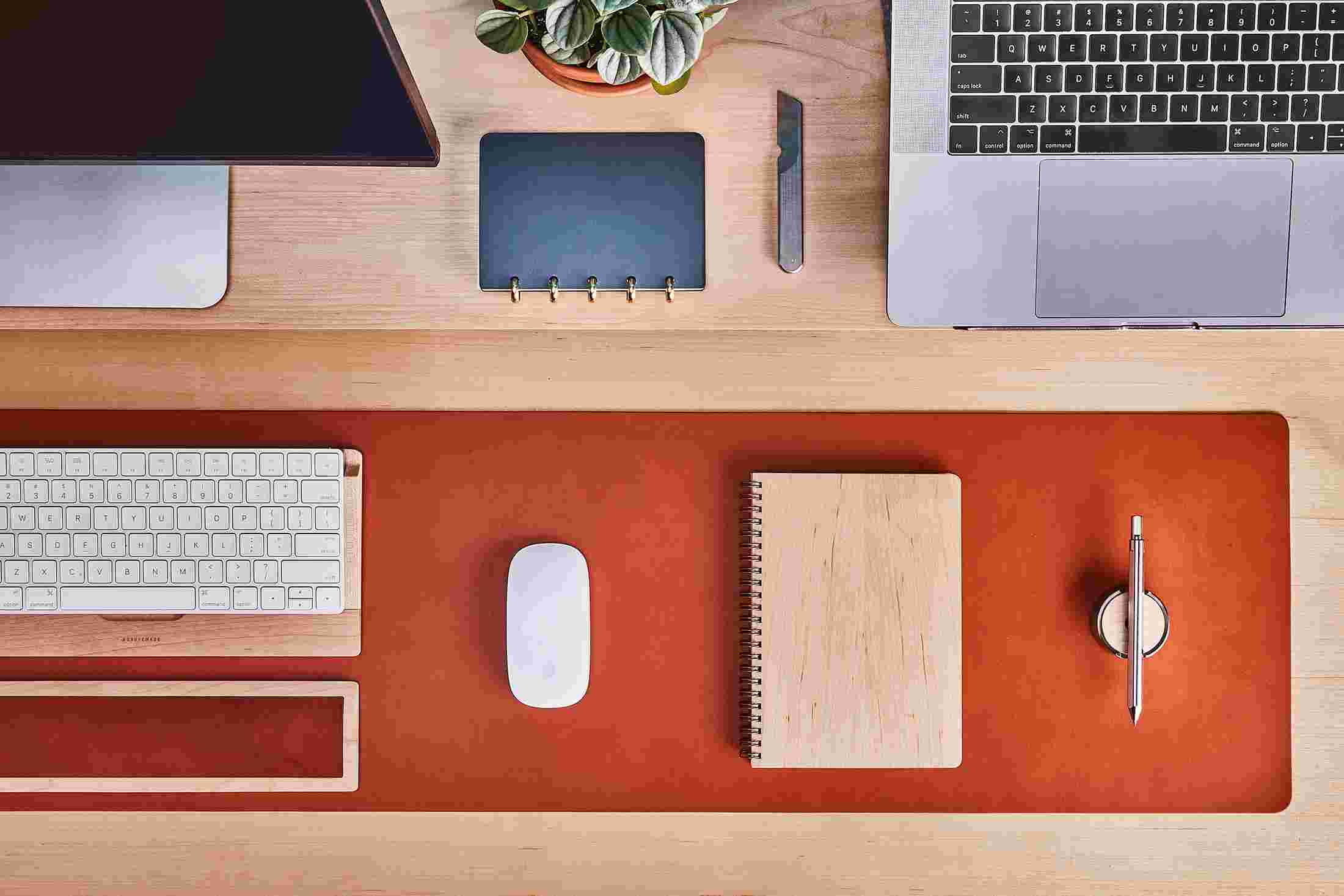 Overhead of maple and leather notebooks on tan leather desk pad with matching maple keyboard tray.