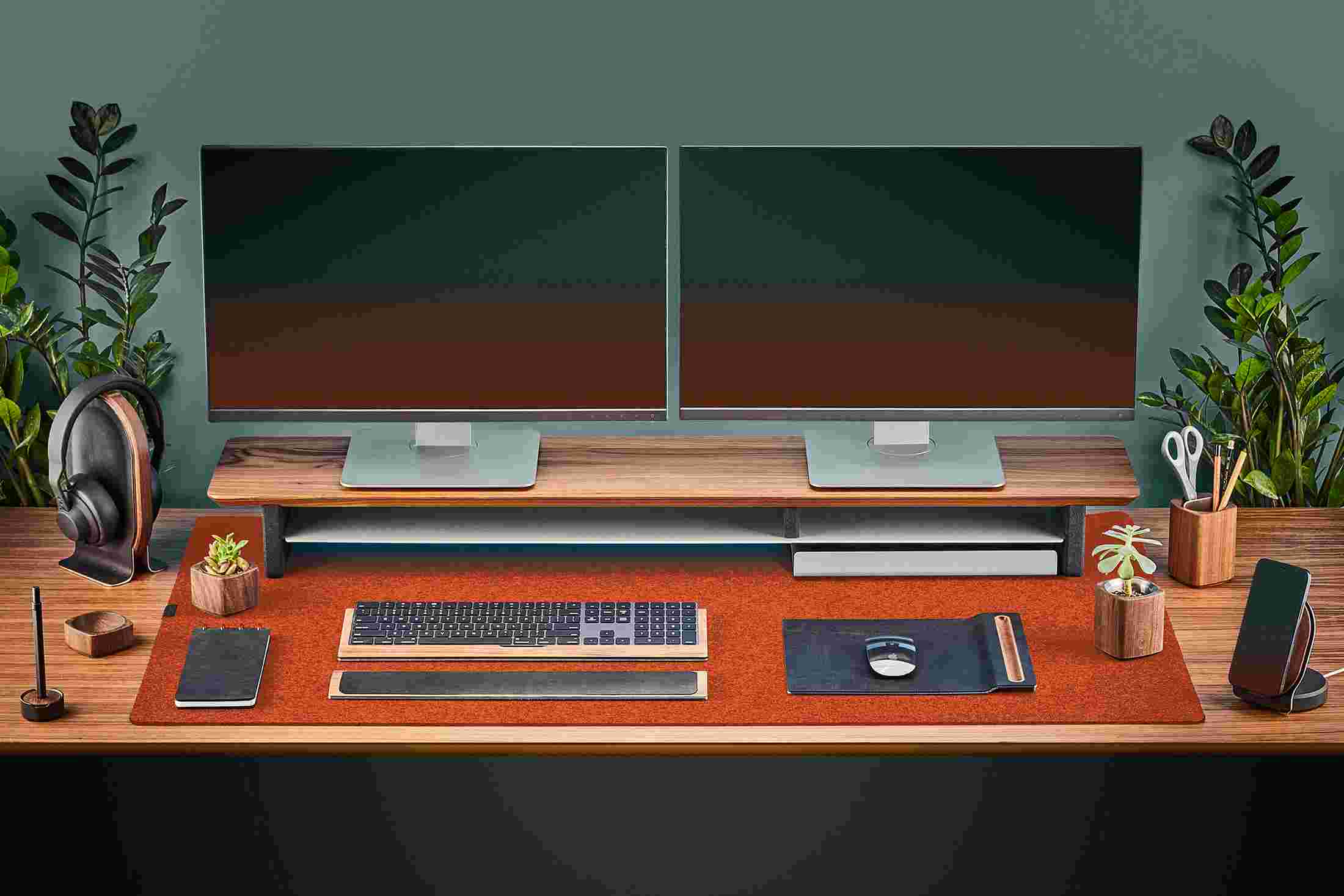 The Extra Large Wool Felt Desk Pad in Dark Orange covering almost an entire desktop, in use with the Walnut Desk Shelf System.