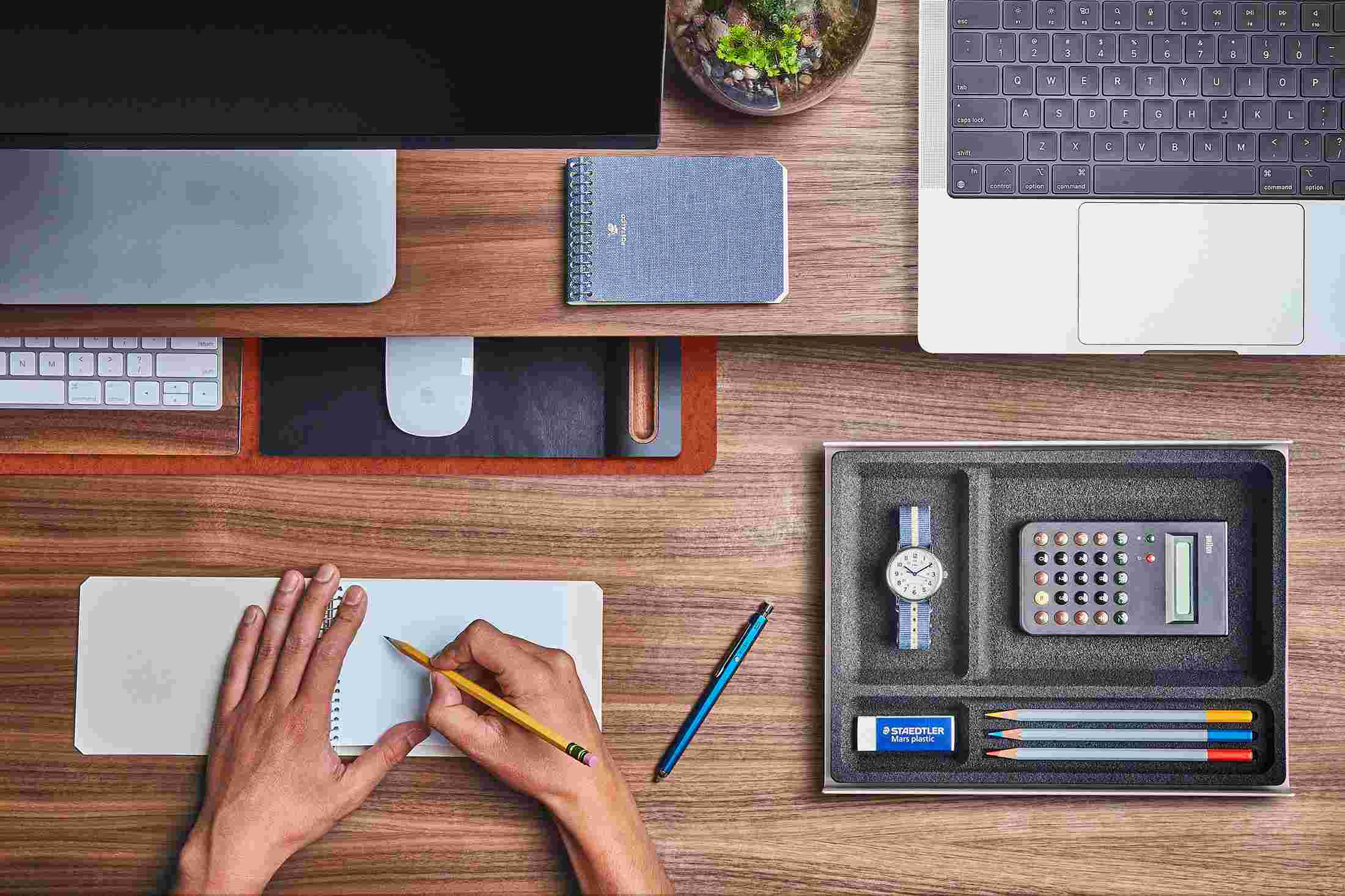 The Small Dark Orange Wool Felt Desk Pad tucked under the Walnut Desk Shelf, creating space to sketch and write.