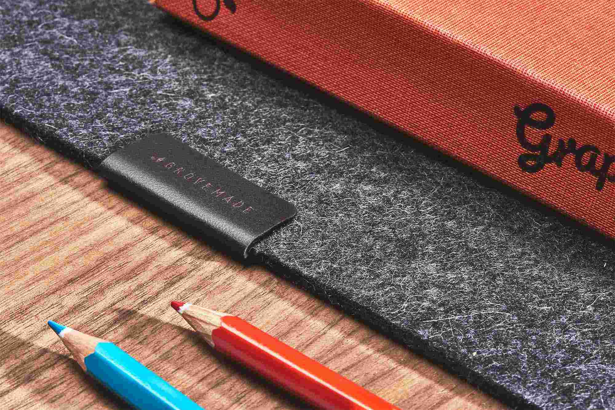Detail of the natural leather tag on the Dark Grey Wool Felt Desk Pad.