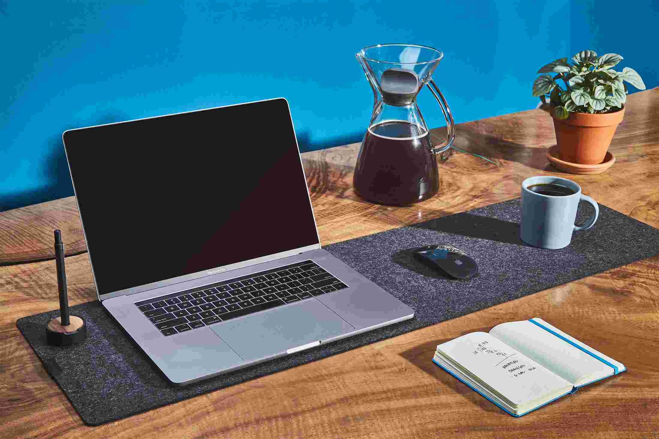 The Medium Dark Felt Desk Pad used as a combination laptop pad, mousepad, and coffee coaster.