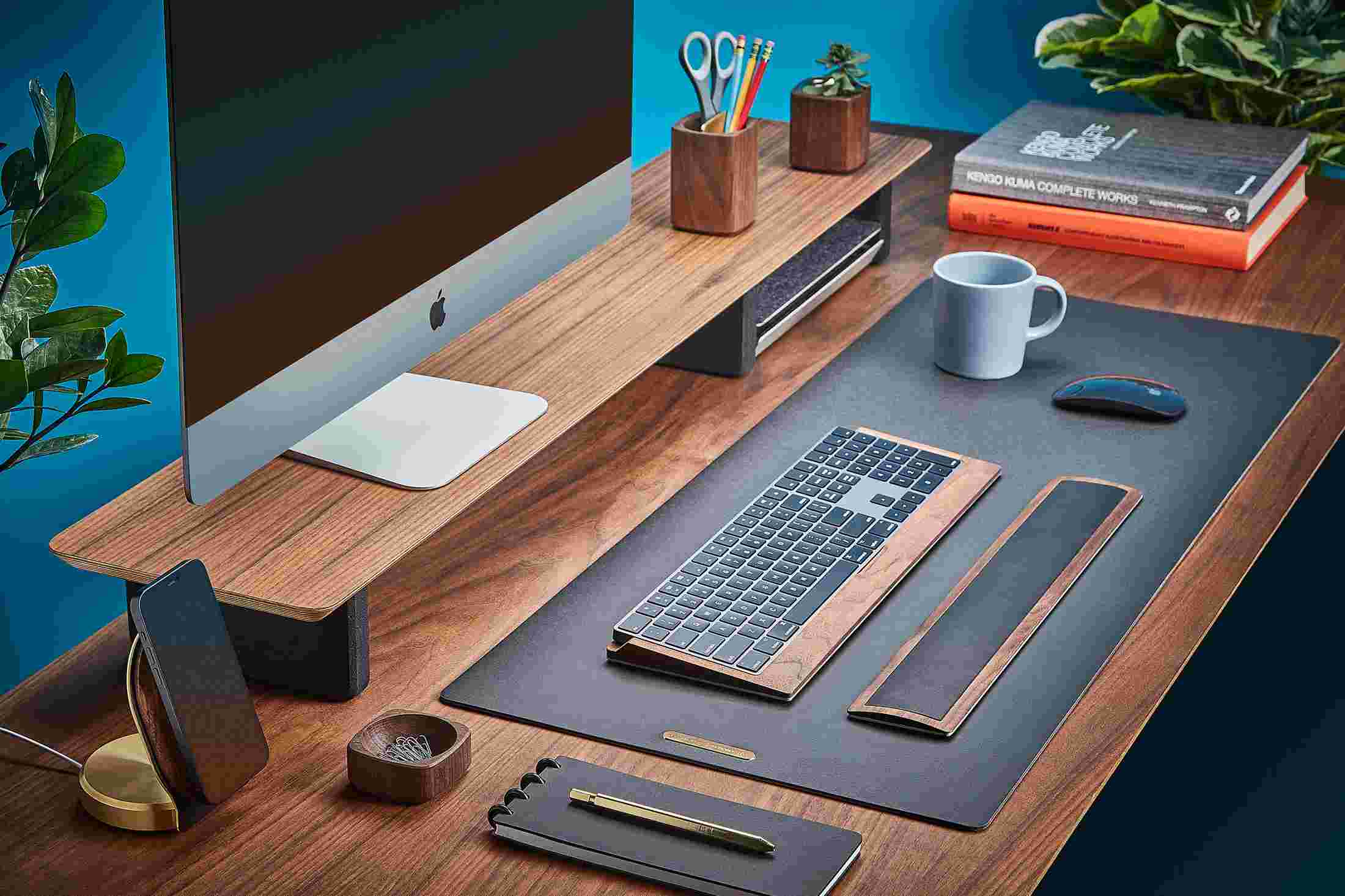 Matte black desk pad on walnut desk with wood accessories.