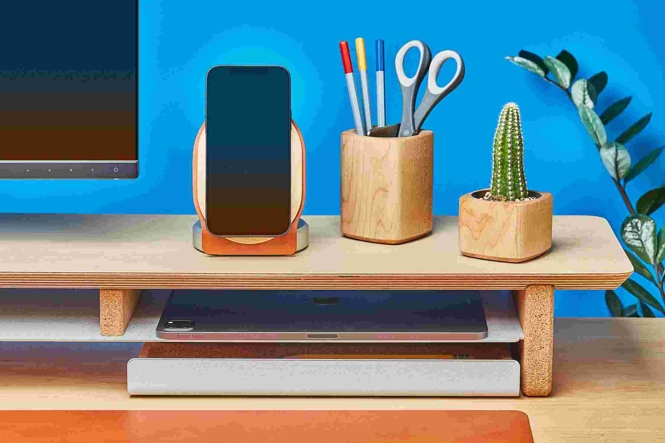 Maple MagSafe Stand for iPhone 12 on wood monitor stand alongside maple planters and premium tan leather desk mat.