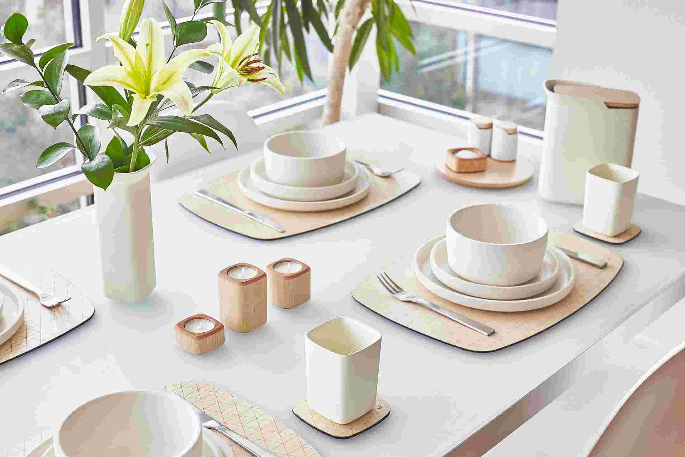 Table set with the Grovemade Maple Tableware collection—white ceramic bowls, cup, water pitcher, and flower vase.