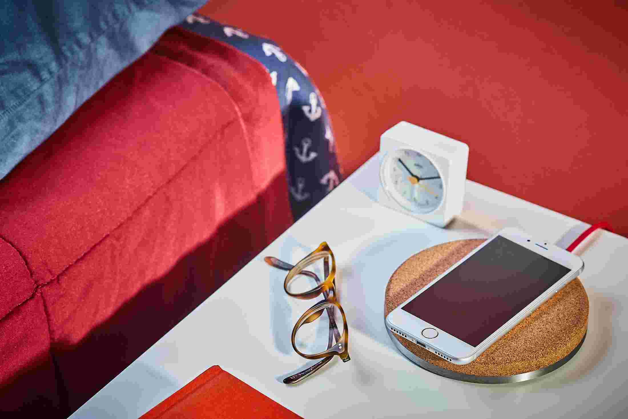 Premium cork charging pad on bedside table charging an iPhone X.