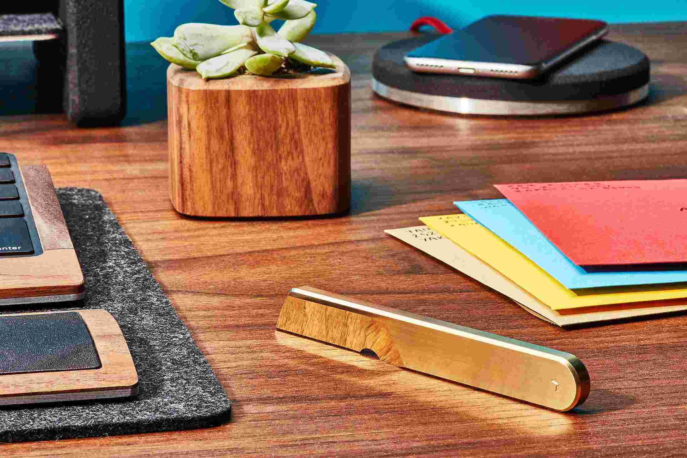 The brass task knife on walnut desk with wood planter.